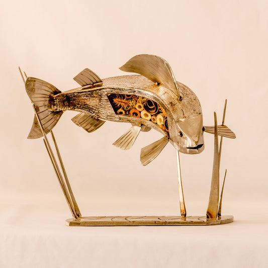 A silver sculpture of a grayling fish with applied scales, mounted on a stand.